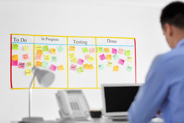 Man working in office with scrum task board on wall - Photo, Image