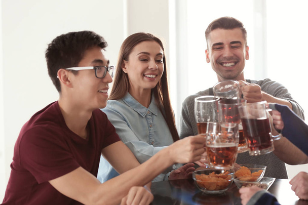 Groep vrienden rammelende brillen met bier in staaf - Foto, afbeelding