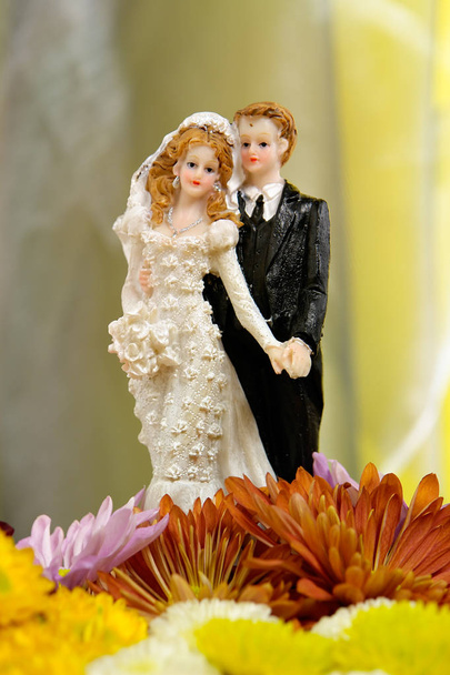 Muñecas de pastel de boda encima de las flores
 - Foto, imagen