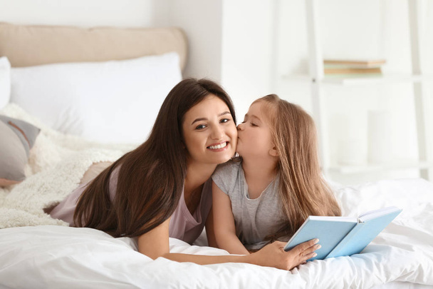 Mother and her daughter reading book together at home - Foto, Imagen