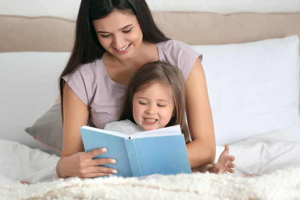 Mother and her daughter reading book together at home - Foto, immagini