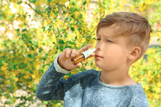 Jongetje met nasale druppels in de buurt van bloeiende boom. Anti-concept - Foto, afbeelding