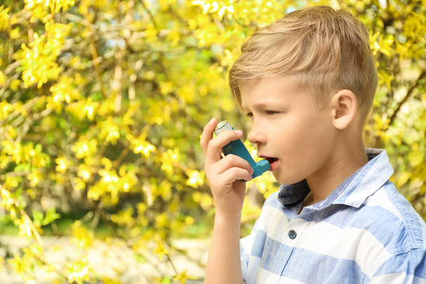 Μικρό αγόρι χρησιμοποιώντας συσκευή εισπνοής κοντά ανθίζοντας δέντρο. Αλλεργία έννοια - Φωτογραφία, εικόνα