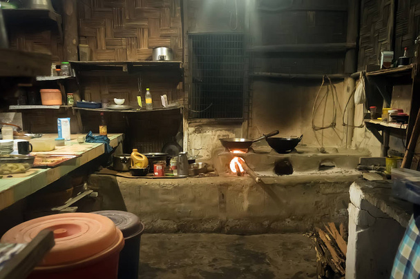 暖炉、喫煙石炭、やかん、フライパン、鍋とヒマラヤの小さなリモート村に古いネパール様式の家で伝統的なキッチン。貧しいアジアの家の内部. - 写真・画像