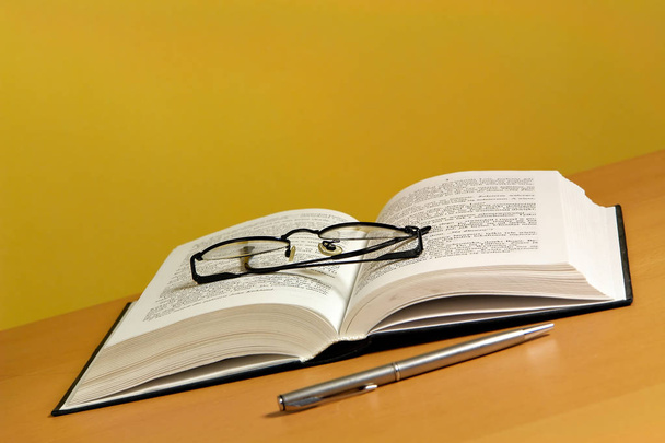 Libro abierto con bolígrafo y gafas
 - Foto, Imagen