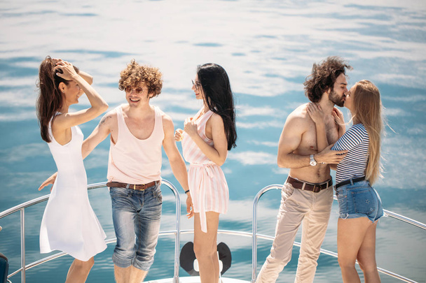Rear view of friends celebrate on sailboat in ocean, arms raised. - Fotó, kép