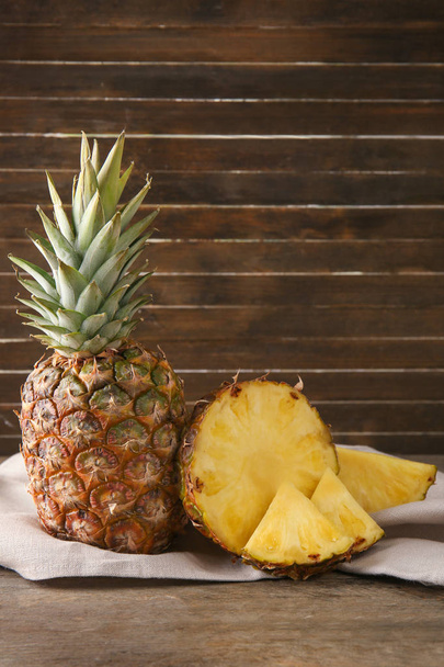 Delizioso ananas con fette sul tavolo contro la parete di legno
 - Foto, immagini