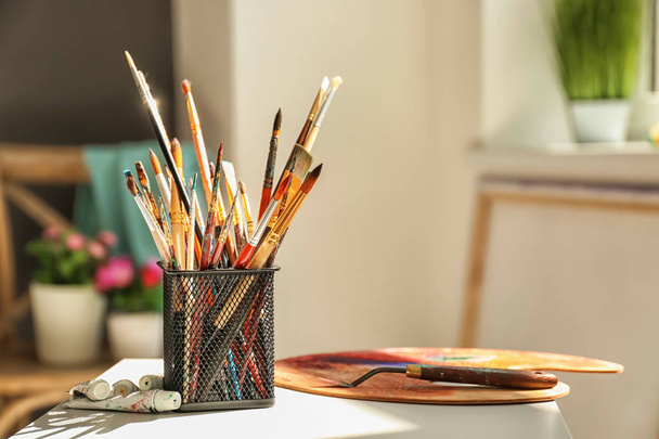 Set van borstels, spatel en palet op tafel in het atelier van de kunstenaar - Foto, afbeelding