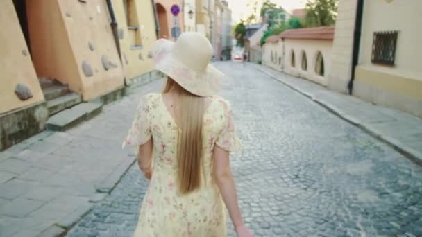Uma mulher sorridente a andar na rua. Mulher bonita alegre em chapéu branco olhando para a câmera enquanto caminhava na cidade
. - Filmagem, Vídeo