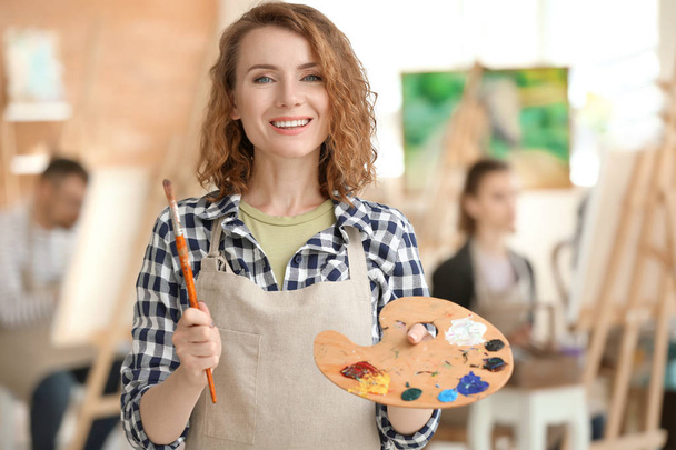 Vrouwelijke artiest met penseel en verf palet in werkplaats - Foto, afbeelding