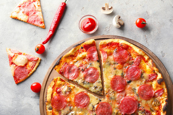 Placa de madeira com pizza de pepperoni saboroso na mesa
 - Foto, Imagem