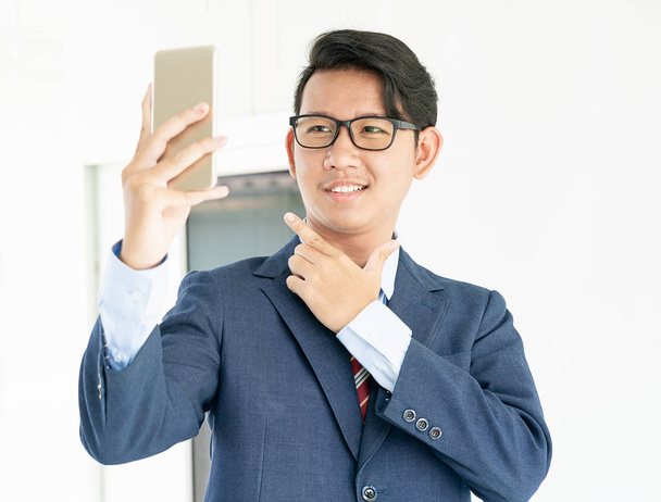 Jeunes hommes d'affaires asiatiques portrait en costume tenant smartphone sur fond blanc
 - Photo, image