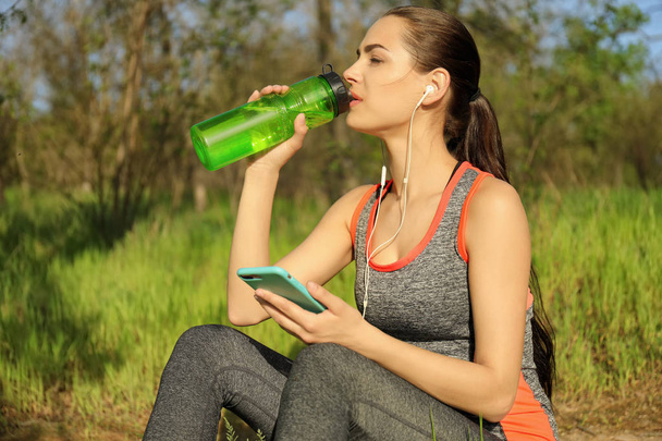 Desportivo jovem mulher beber água depois de correr no parque
 - Foto, Imagem
