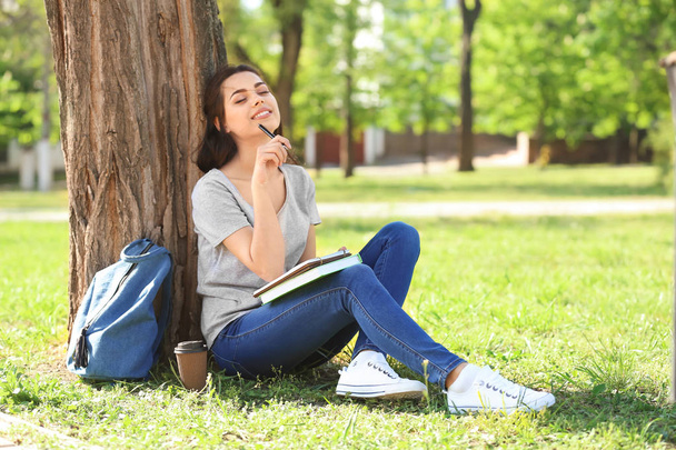 Beautiful young woman with notebook resting in park - Photo, Image