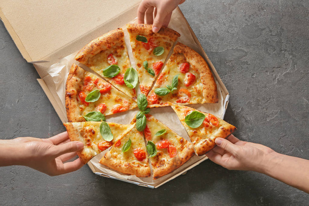 Jugendliche nehmen leckere Pizza-Margherita-Scheiben aus Schachtel - Foto, Bild