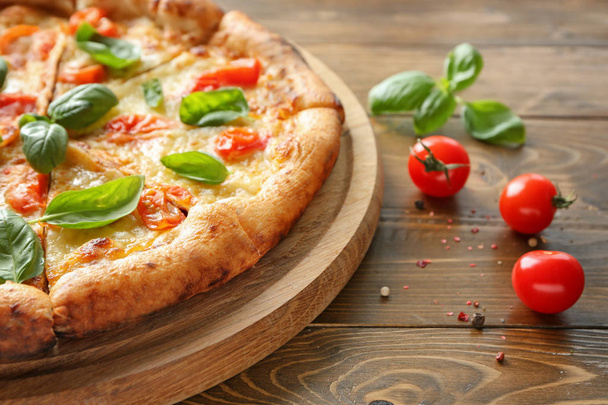 Board with delicious pizza Margherita on wooden background, closeup - Фото, зображення