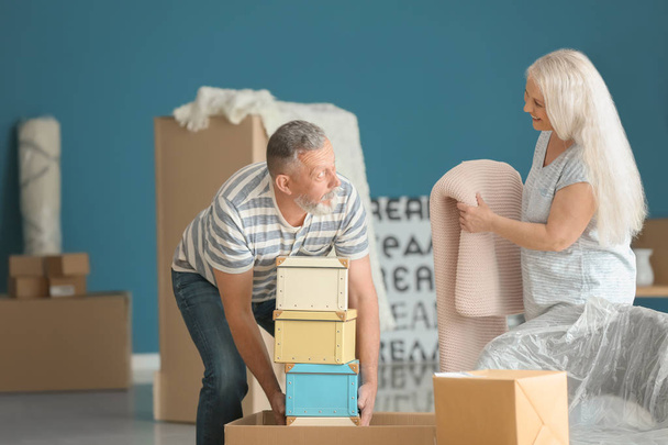 Mature couple with moving boxes at new home - Фото, изображение