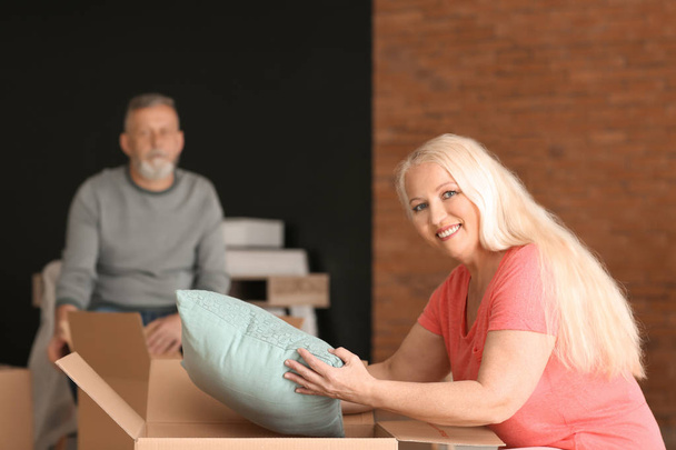 Mulher madura desempacotando caixa em movimento na nova casa
 - Foto, Imagem