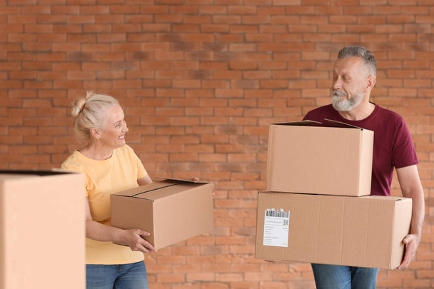 Mature couple with moving boxes at new home - Foto, imagen