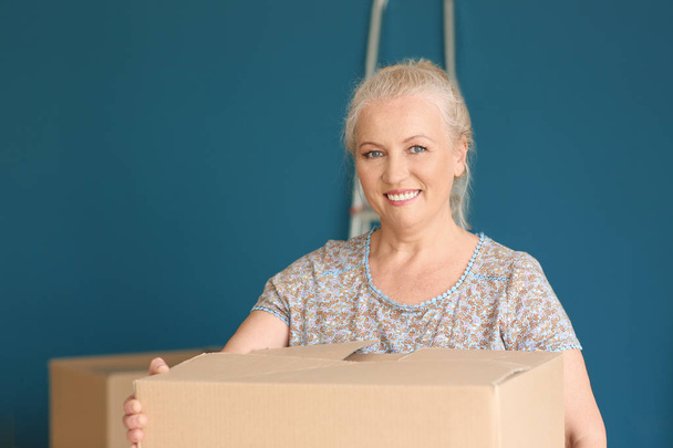Mature woman with moving box at new home - 写真・画像