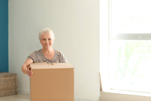 Mature woman with moving box at new home - Zdjęcie, obraz