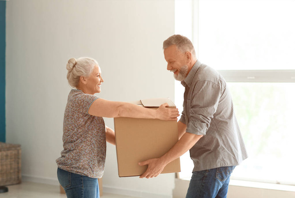 Mature couple with moving box at new home - Photo, Image