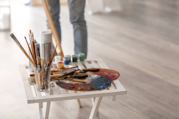 Стол с инструментами и красками в мастерской художника
 - Фото, изображение