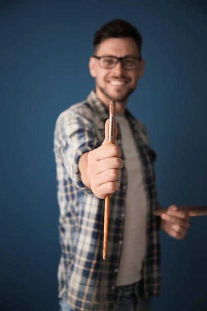 Muž umělec držet štětec na barvu pozadí - Fotografie, Obrázek