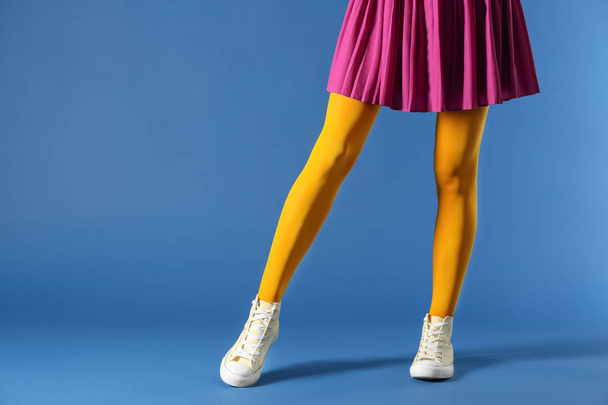 Legs of beautiful young woman wearing tights and skirt on color background - 写真・画像
