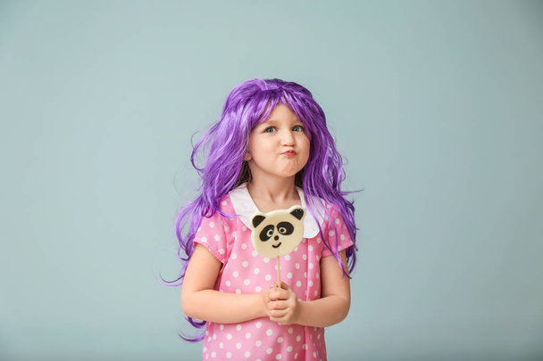 Χαριτωμένο μικρό κορίτσι σε μωβ περούκα και με το lollipop με χρώμα φόντου - Φωτογραφία, εικόνα