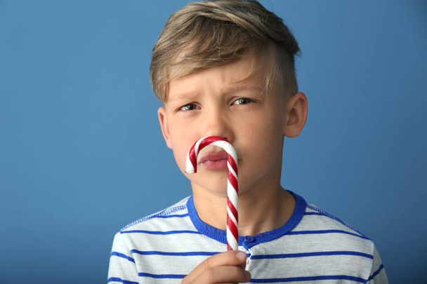 Cute little boy with candy cane on color background - Foto, imagen