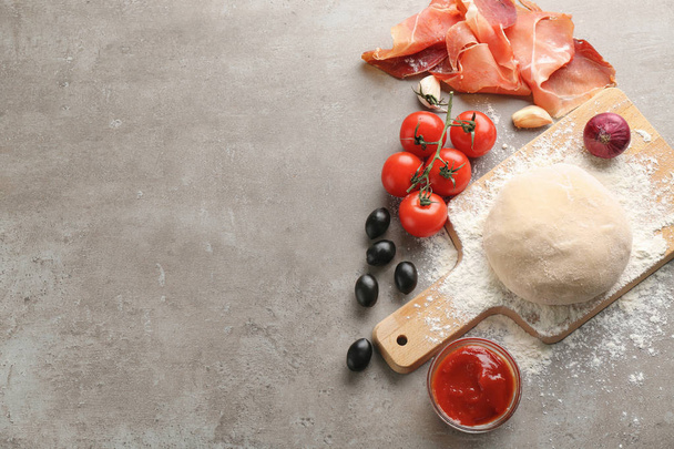 Massa crua com ingredientes para pizza na mesa
 - Foto, Imagem