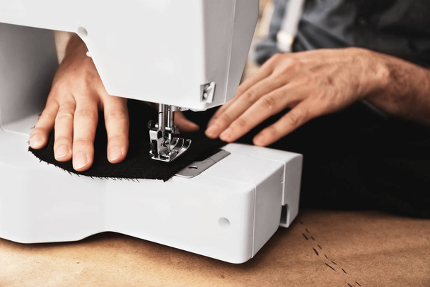 Joven sastre trabajando en la máquina de coser en atelier, primer plano
 - Foto, imagen