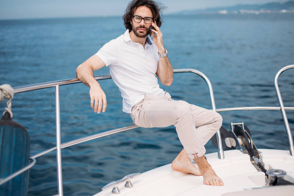 Young bearded man on a luxury yacht with a magnificent view of the sea. - Φωτογραφία, εικόνα
