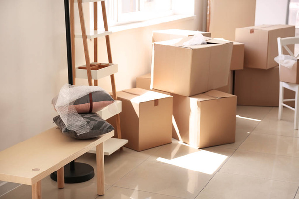 Carton boxes and interior items on floor in room. Moving house concept - Foto, Bild