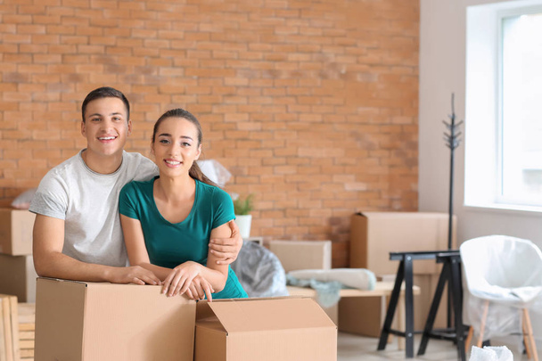 Νεαρό ζευγάρι με κουτιά σε εσωτερικούς χώρους. Μετακίνηση σε νέο σπίτι - Φωτογραφία, εικόνα