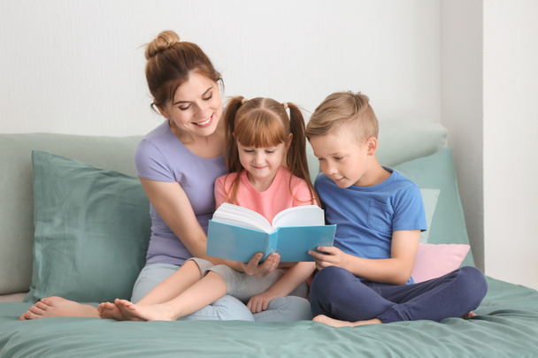 Mutter und ihre Kinder lesen zu Hause gemeinsam Buch - Foto, Bild