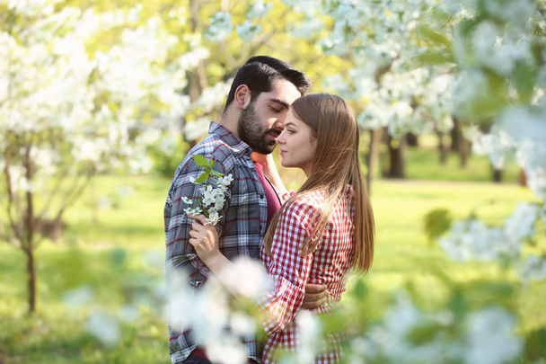Joyeux jeune couple près de l'arbre en fleurs dans le parc le jour du printemps
 - Photo, image