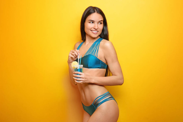 Beautiful young woman in bikini and with drink on color background - Photo, Image