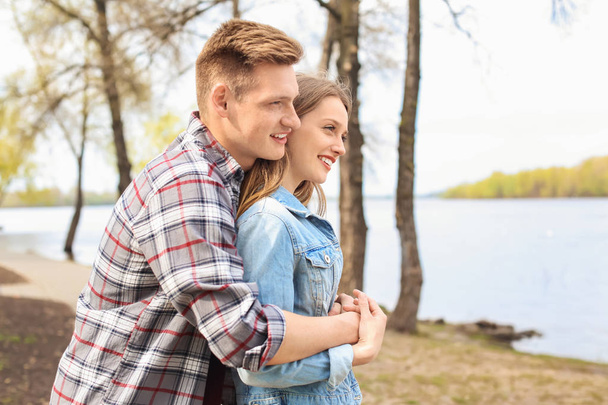 glückliches junges Paar in der Nähe des Flusses an einem Frühlingstag - Foto, Bild