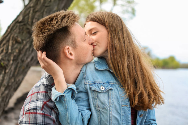 glückliches junges Paar küsst sich am Frühlingstag in der Nähe des Flusses - Foto, Bild