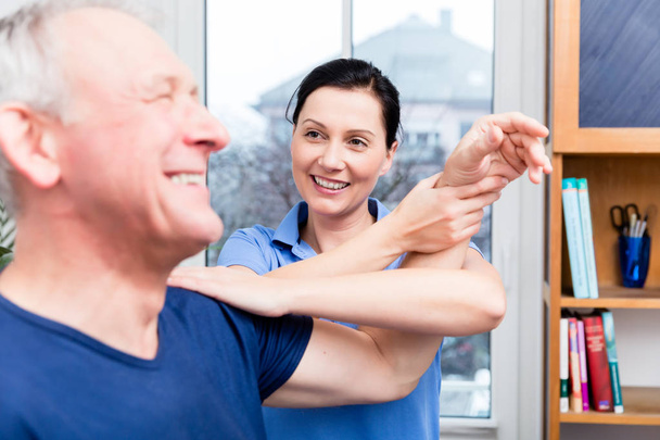 Paciente de edad avanzada haciendo ejercicio de hombro bajo la ayuda del terapeuta
 - Foto, Imagen
