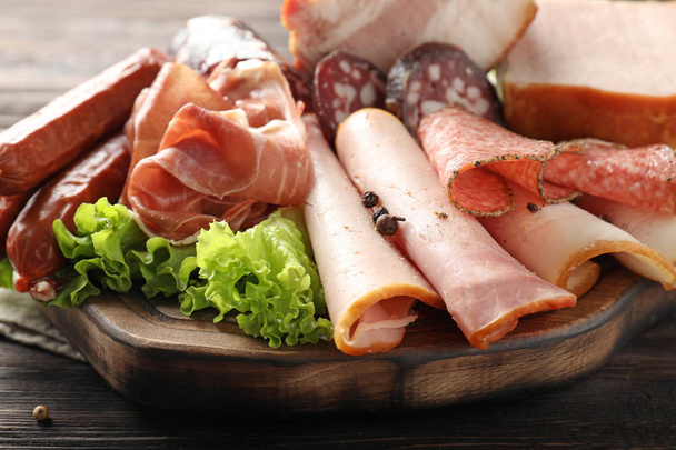 Wooden board with assortment of delicious deli meats on wooden board - Фото, изображение