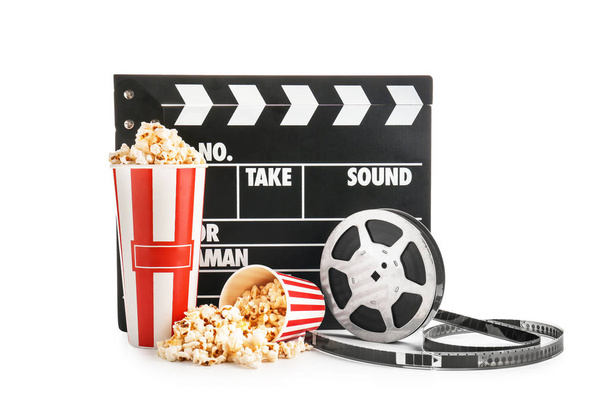 Cups with tasty popcorn, film reel and clapperboard on white background - Photo, Image