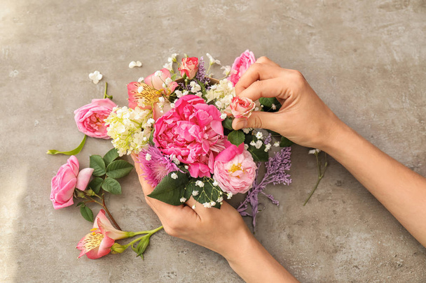 Female florist preparing box with beautiful flowers on table, closeup - Foto, imagen