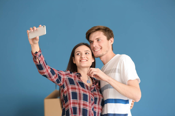 Joven pareja feliz tomando selfie con la llave de su nueva casa en el interior
 - Foto, imagen