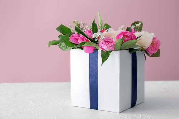 Подарочная коробка с красивыми пионскими цветами на столе на фоне цвета
 - Фото, изображение