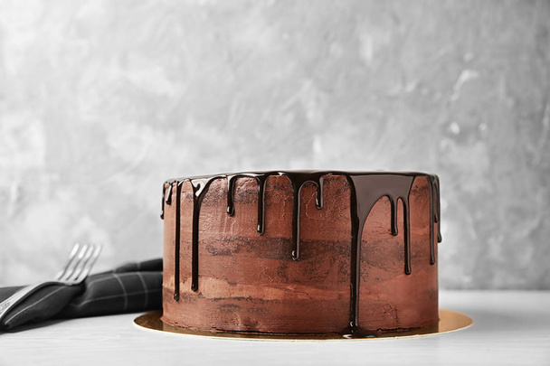 Placa con delicioso pastel de chocolate en la mesa sobre fondo claro
 - Foto, Imagen