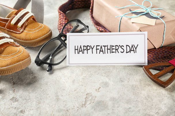 Composition with gift box, male accessories and baby shoes on grey textured background. Happy Father's Day celebration - Fotografie, Obrázek