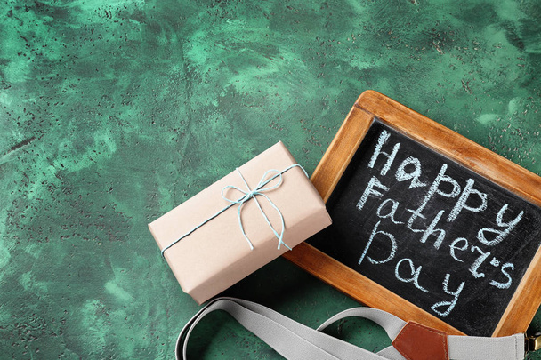 Happy Father 's Day inscription on chalkboard with susenders and gift box on color textured background
 - Фото, изображение